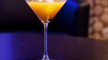 Ein Martini-Glas mit Trinkhalm auf einem dunklen Tisch.