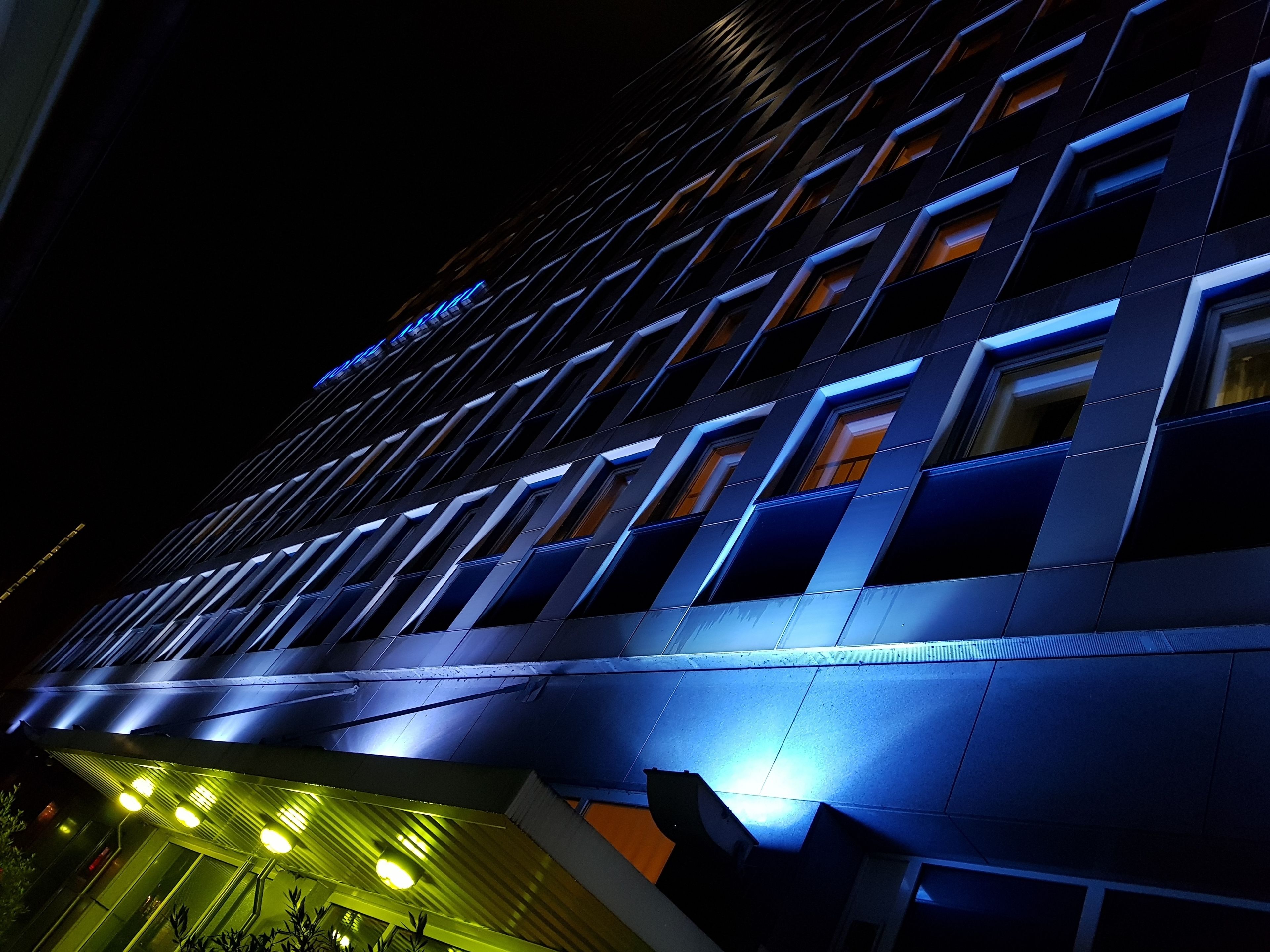 A modern building with a geometric facade and illuminated windows at night.