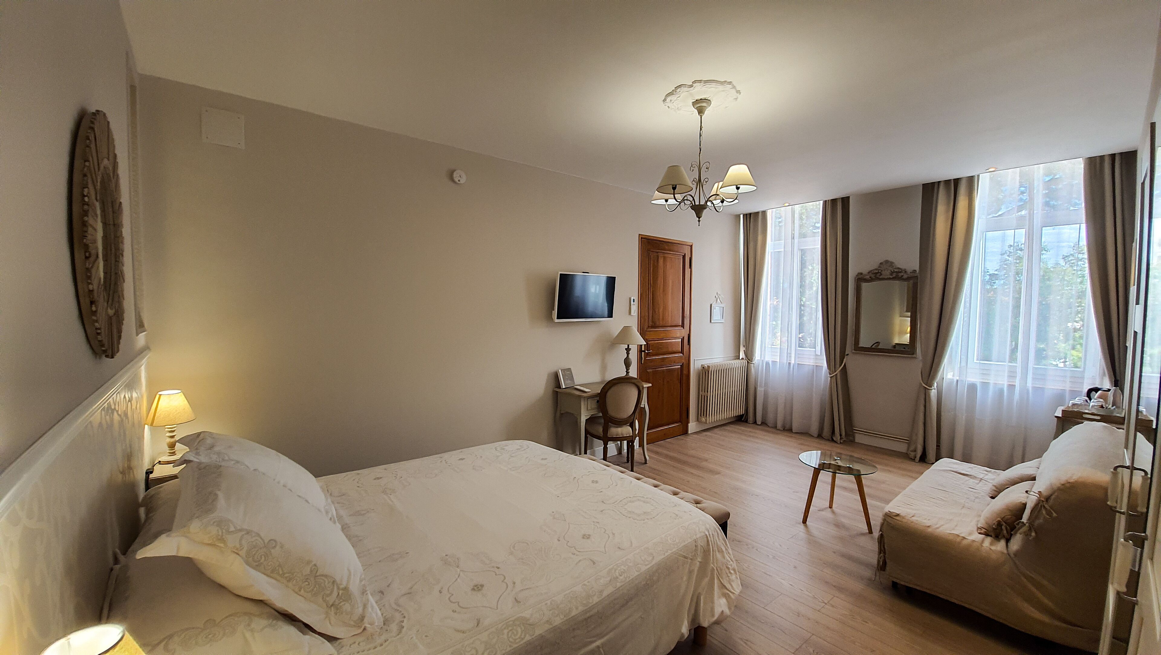 Une chambre d’hôtel avec deux lits, un bureau, une chaise, une télévision et une fenêtre avec des rideaux.