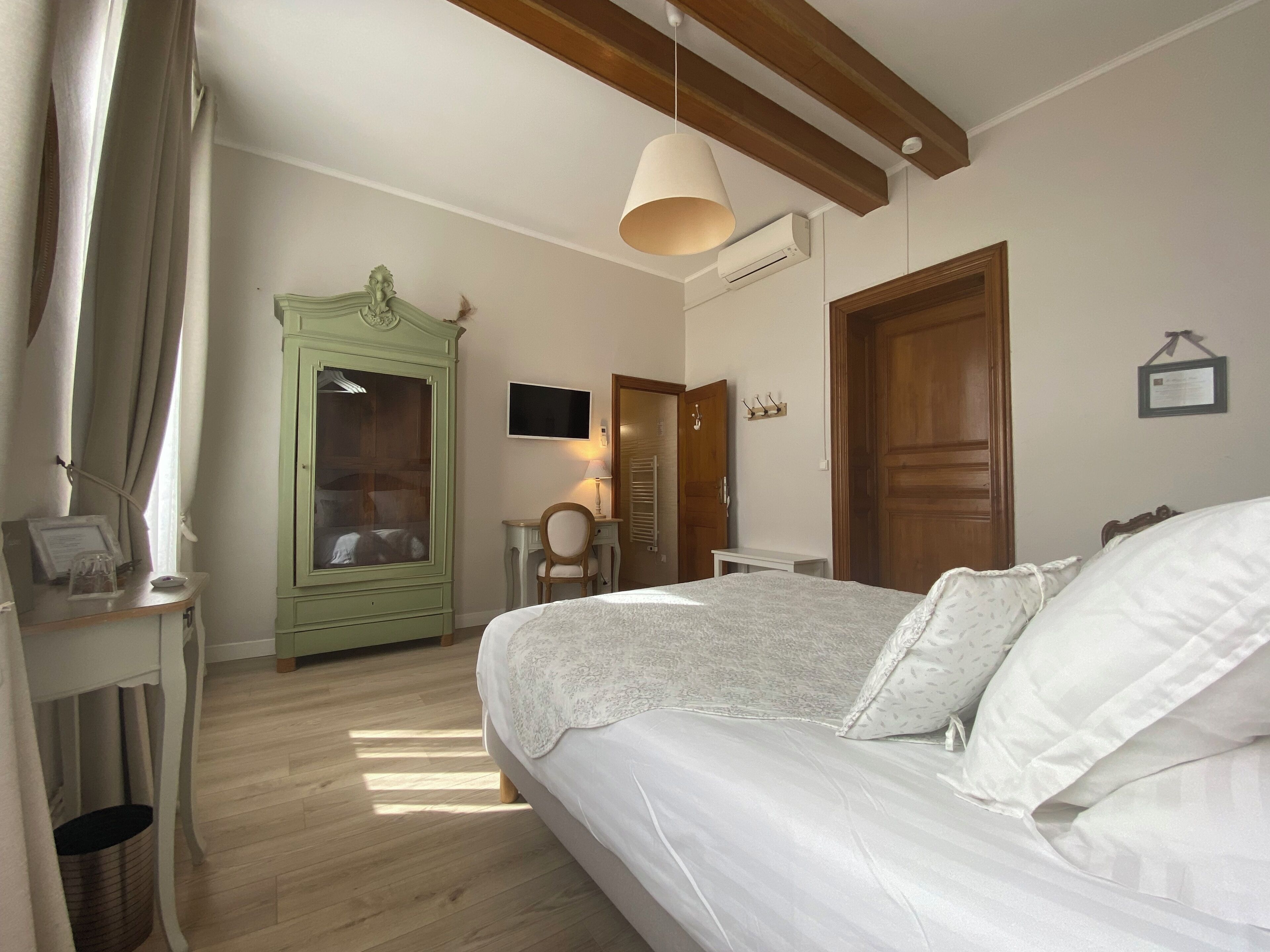 A bedroom with a bed, a desk, a wardrobe, and a television.