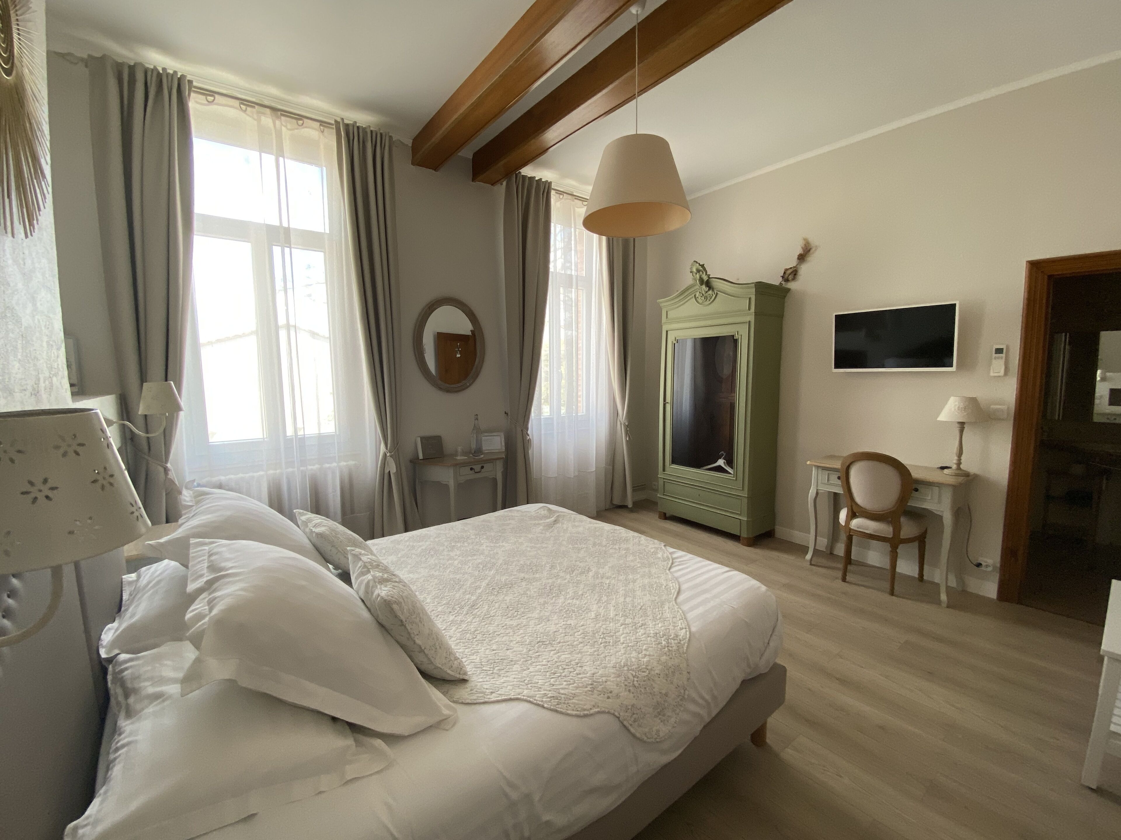 A bedroom with a bed, a desk, a wardrobe, and a TV.