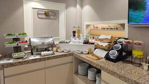 A modern breakfast bar with a coffee machine, a variety of food options, and a flat-screen TV mounted on the wall. - Gemlik Pasa Hotel (Gemlik)