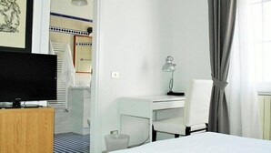 A hotel room with a bed, a desk, a chair, a TV, and a window with curtains. - Vittorino Guest House (Rome)