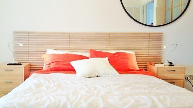 A neatly made bed with white and red bedding, wooden headboard, bedside tables, and a round mirror on the wall. - Vittorino Guest House (Rome)