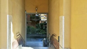 A narrow stairway with a handrail, leading to an outdoor area with plants and a view of buildings. - Vittorino Guest House (Rome)