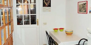 A dining area with a white table, two chairs, and a white cabinet with glass doors. - Vittorino Guest House (Rome)