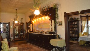 A traditional room with a large wooden cabinet, a small table with a tablecloth, a chair, and a bookshelf. - The Carleton House (Bonham)