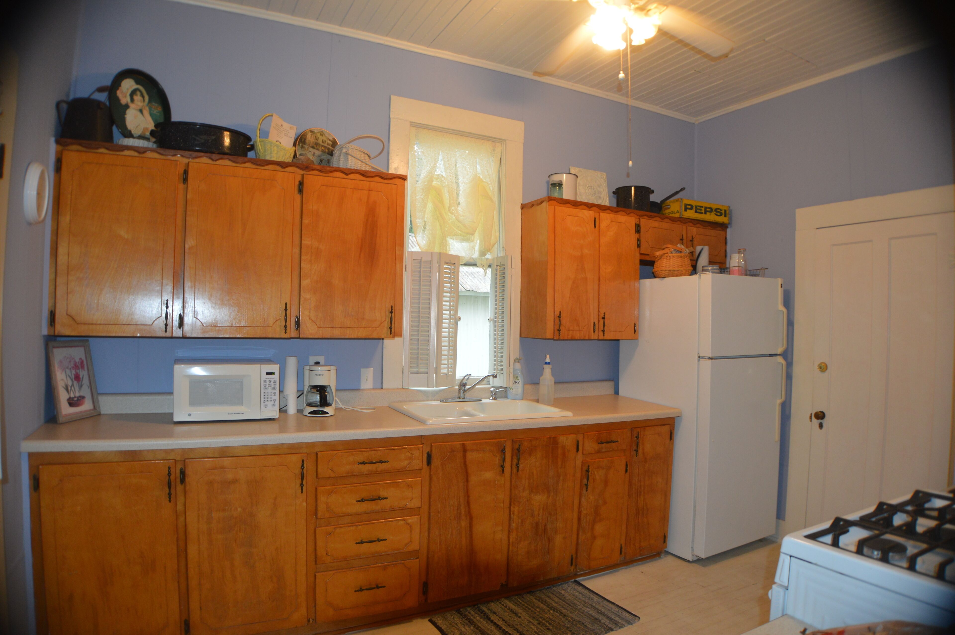 A kitchen with wooden cabinets, a white refrigerator, a microwave, and a gas stove.