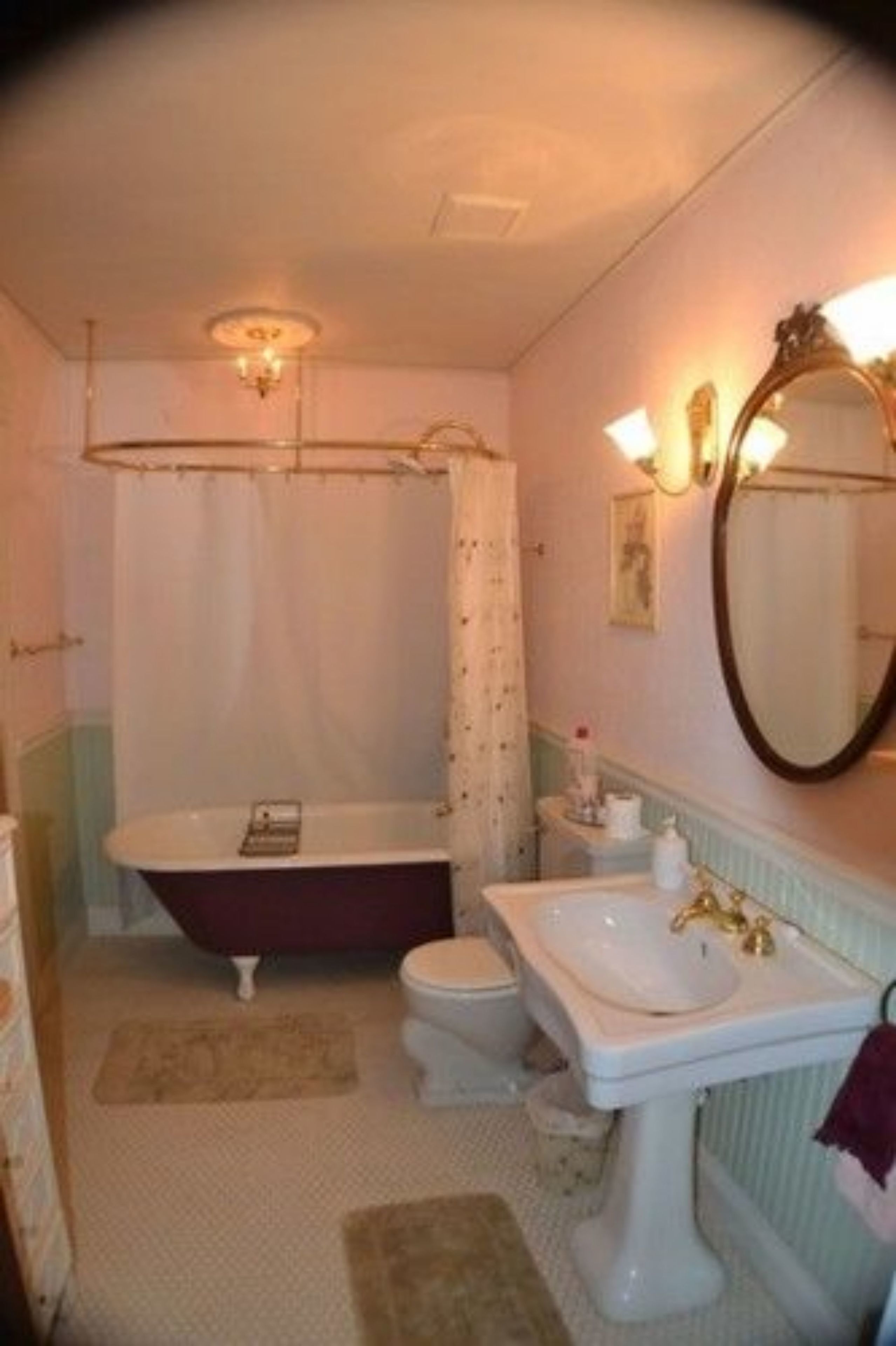 A bathroom with a bathtub, toilet, and sink, featuring a mirror and a light fixture above the sink.