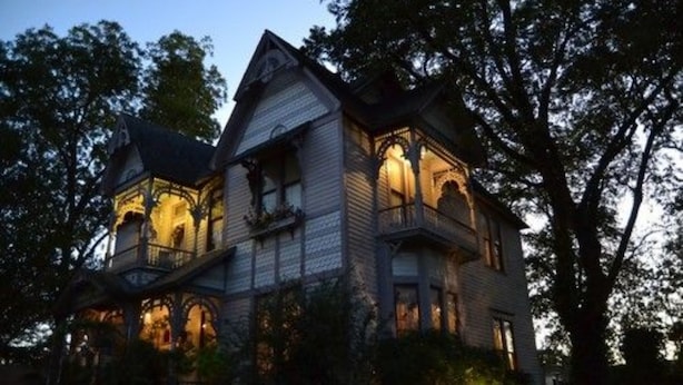 A large, two-story house with a steeply pitched roof, multiple windows, and a balcony. - The Carleton House (Bonham)