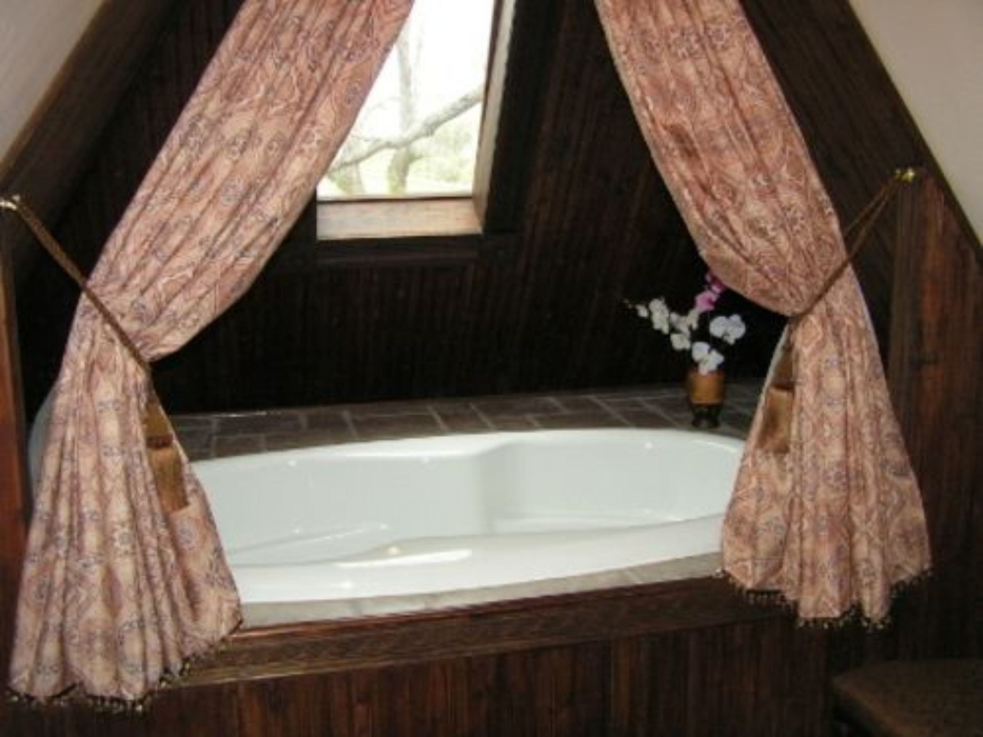 Un baño con bañera, ventana y cortina.
