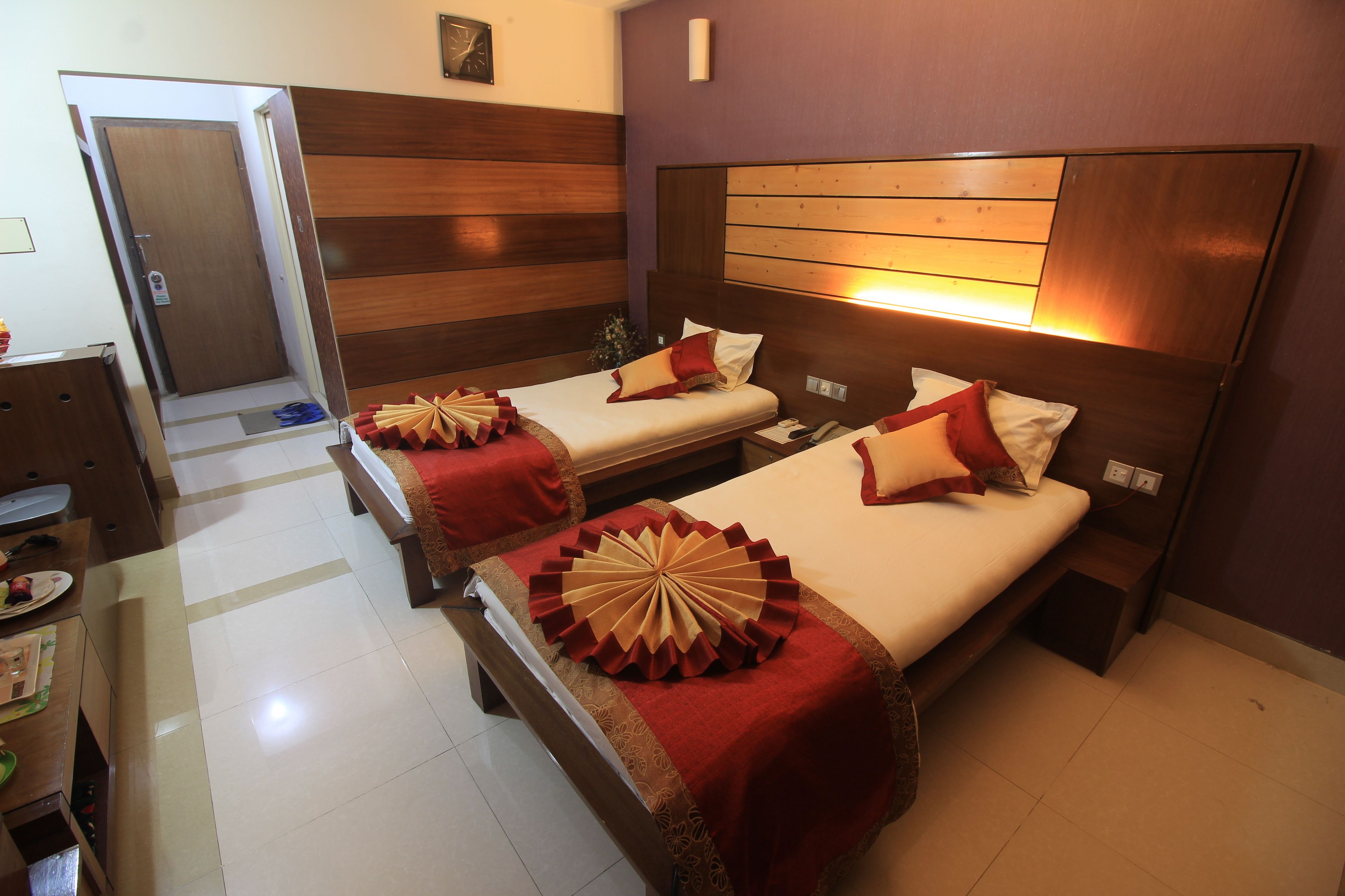 Een hotelkamer met twee bedden, houten hoofdeinden en een rood-beige sprei.