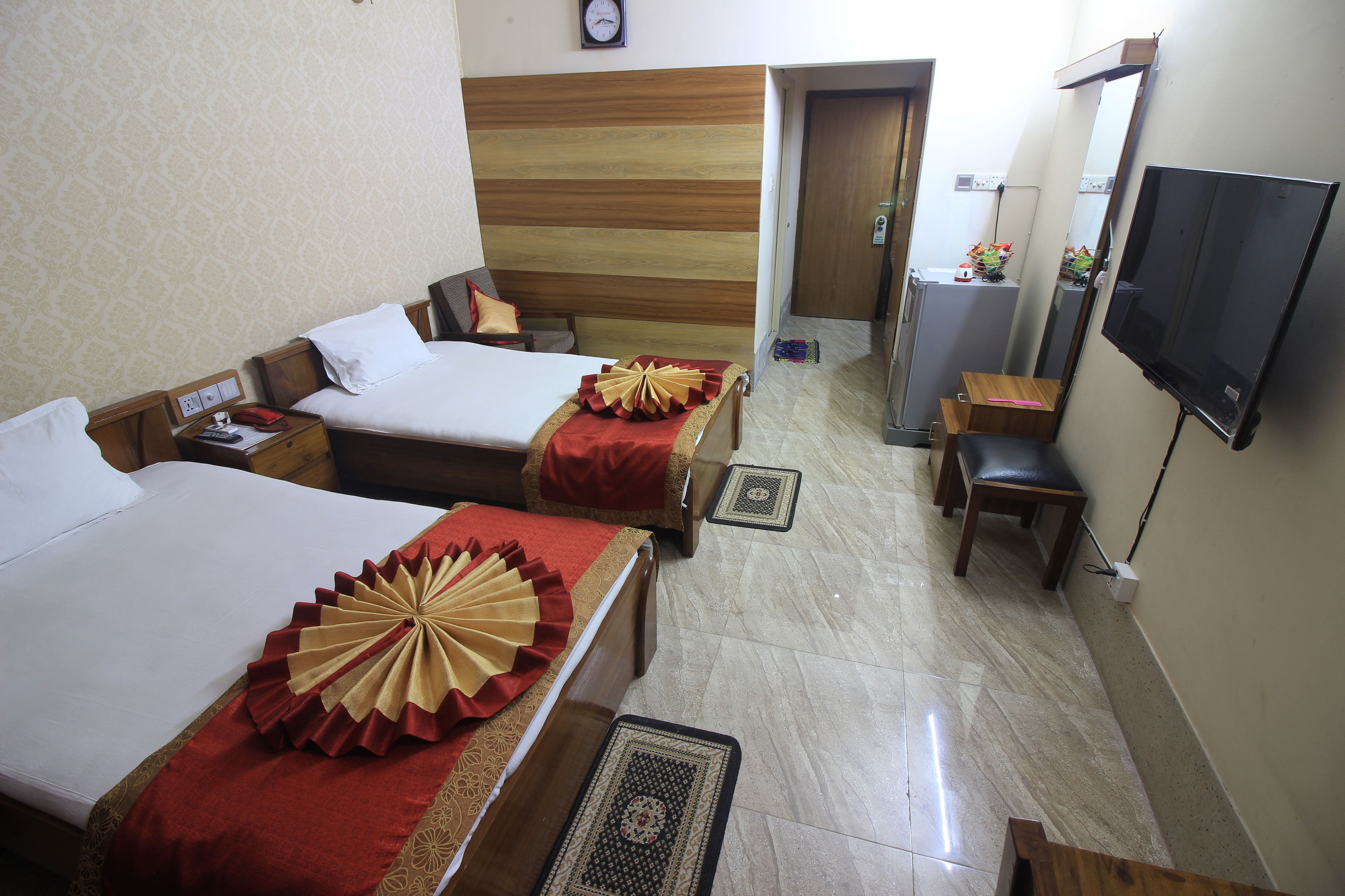 A hotel room with two beds, a TV, a desk, and a chair.