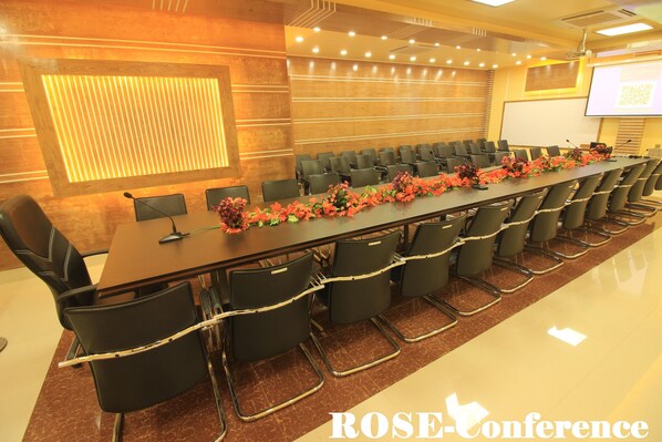 A conference room with a long table, chairs, and a projector screen.
