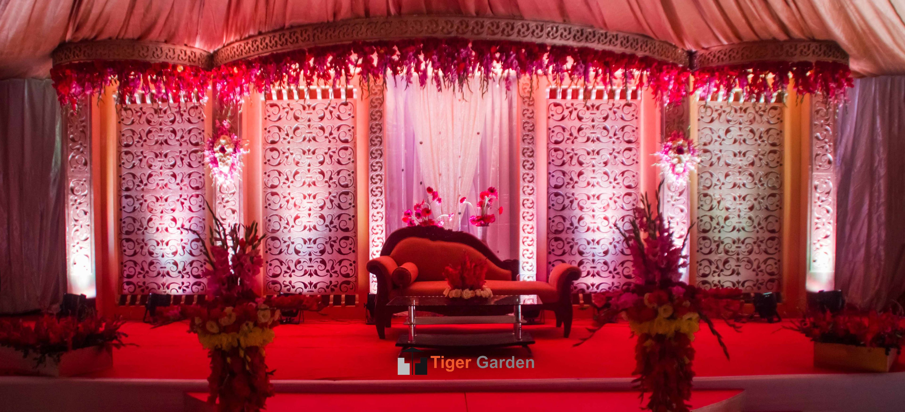 Un palco con una poltrona rossa, pannelli decorativi e composizioni floreali.