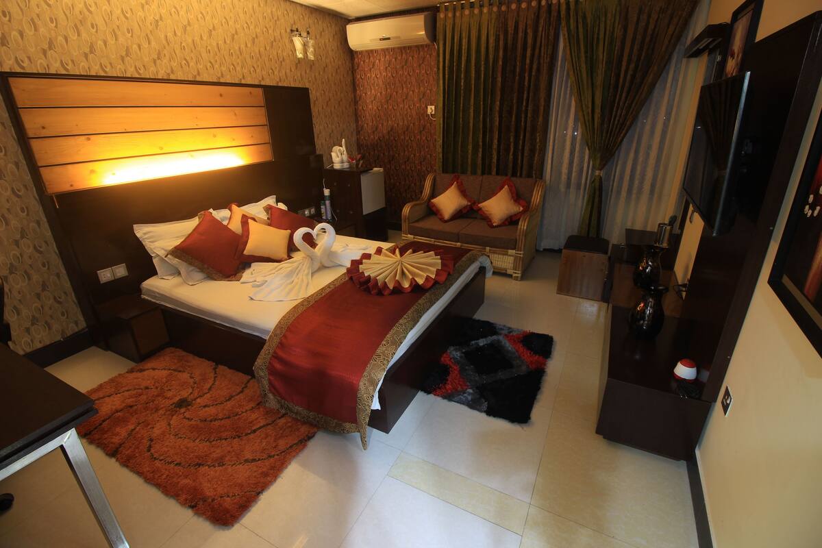 Une chambre d’hôtel avec un grand lit, un canapé, une télévision et un bureau.