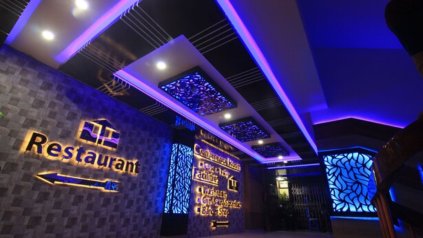 A modern restaurant interior with a neon sign, a reception area, and a list of amenities including a conference room, facilities, and a barber shop.