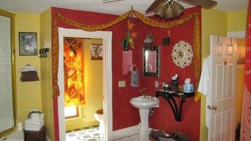 A bathroom with a red accent wall, a white sink, a ceiling fan, and a tiled floor.