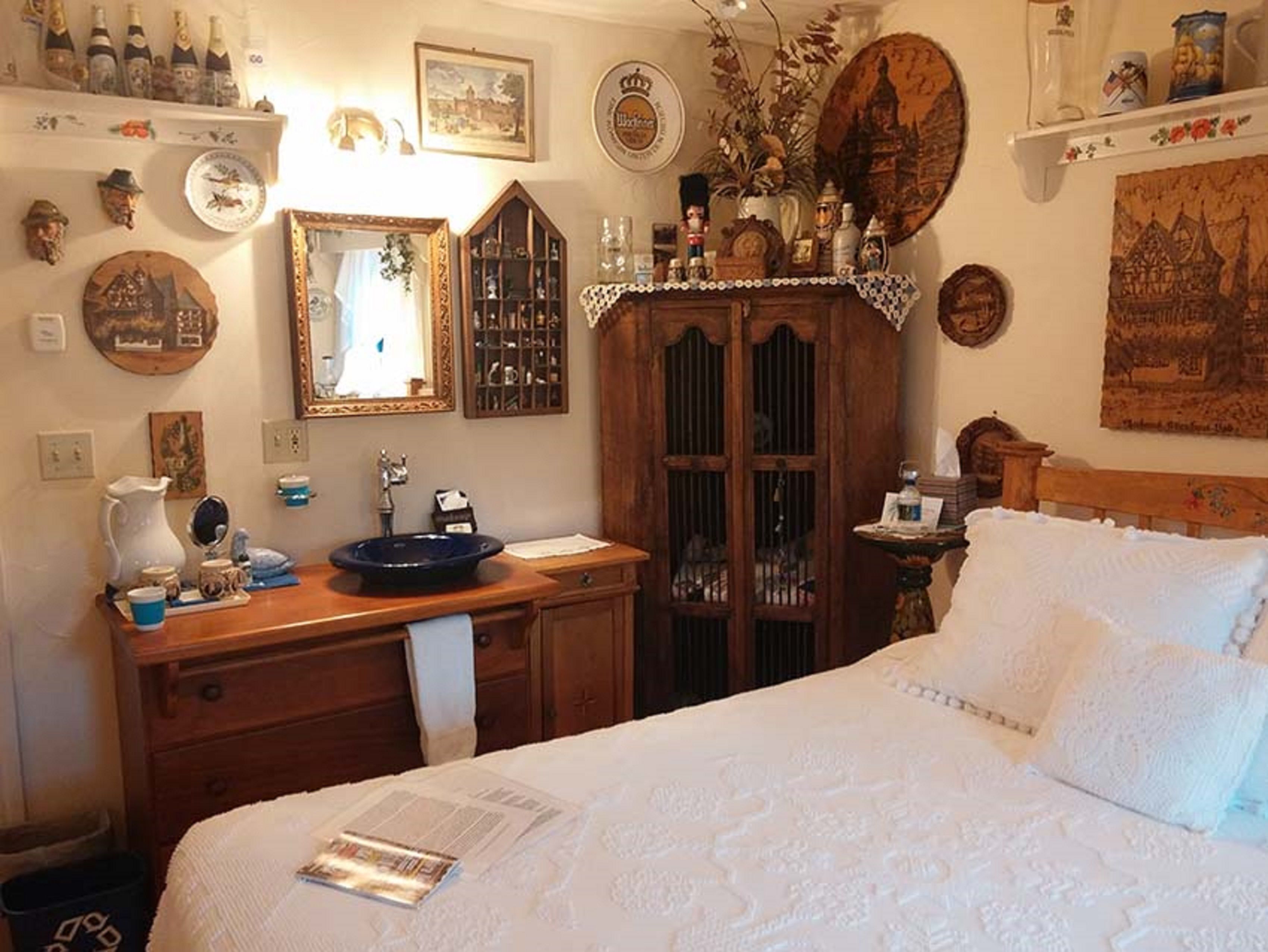 Une chambre à coucher comprenant un lit, une commode en bois, un miroir et divers objets décoratifs accrochés aux murs.