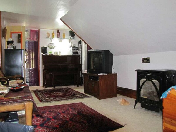 Uma sala de estar com televisão, lareira e um armário de madeira.
