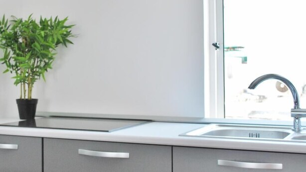 A modern kitchen with a glass backsplash, a stainless steel sink, and a potted plant. - Peneco Albufeira GuestHouse - Hostel (Albufeira)