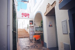 A narrow alleyway with a restaurant sign, a hostel sign, and a staircase leading to a building. - Peneco Albufeira GuestHouse - Hostel (Albufeira)