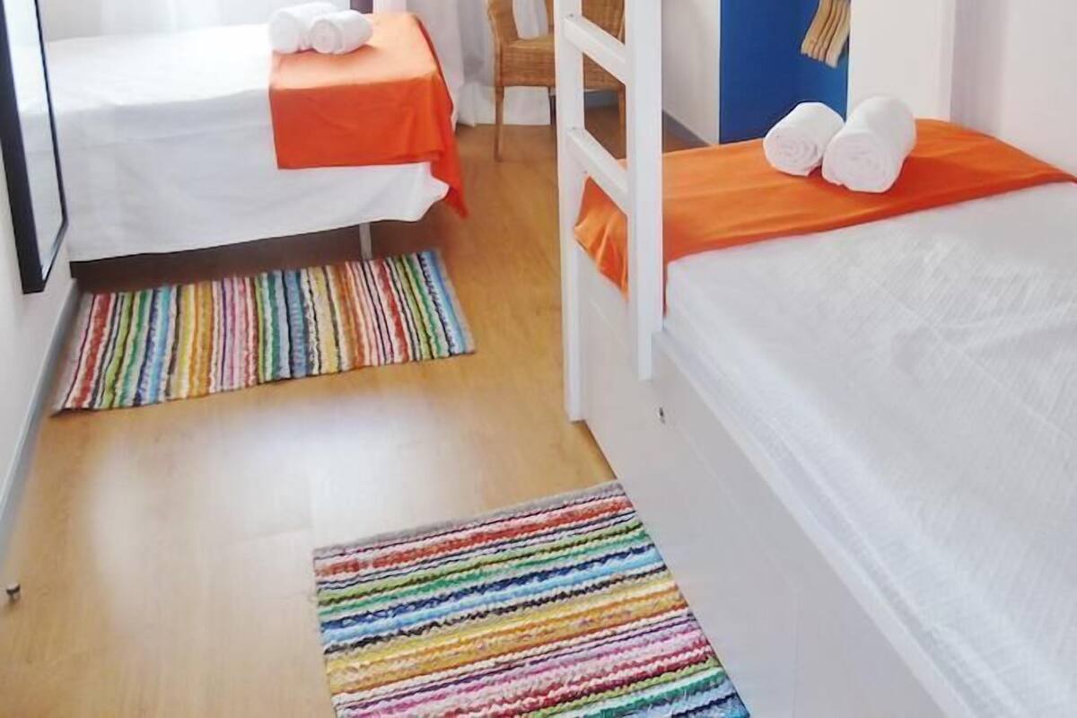 A room with two beds, a chair, and a bunk bed.