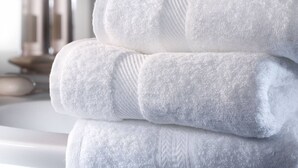 A stack of white towels with a textured pattern, placed on a white surface. - Monolocale Rosso (Turin)