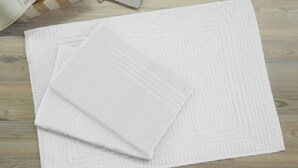 A stack of white textured mats on a wooden floor. - Monolocale Rosso (Turin)