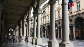 A covered pedestrian walkway with columns, leading to a building with classical architecture. - Monolocale Rosso (Turin)