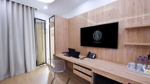 A modern hotel room with a wooden desk, a laptop, a phone, and a coffee tray with cups and a box of tissues. - Arabella Residence (New Cairo)