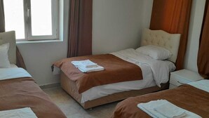 A hotel room with two beds, each with a brown bedspread and white pillows. There is a window with curtains, and a nightstand with a lamp. - Sunrise Güneş Motel (Pütürge)