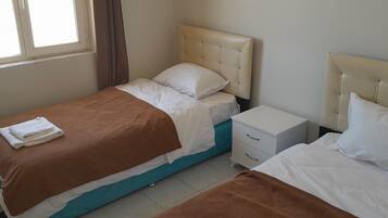 Un dormitorio doble con dos camas, una mesita de noche y una ventana.