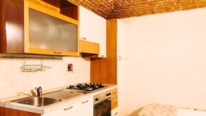 Une cuisine de taille réduite, équipée d’une cuisinière à gaz, d’un évier et de meubles de rangement en bois.