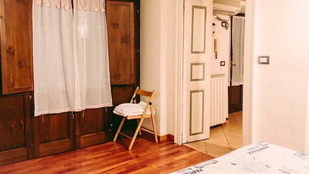 Une pièce dotée d’un plancher en bois, d’une armoire en bois, d’une chaise et d’une porte donnant sur une autre pièce.