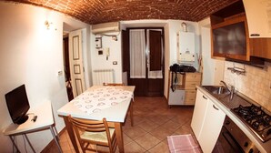 Une cuisine de taille réduite comprenant une table à manger, des chaises, une cuisinière et un petit réfrigérateur.