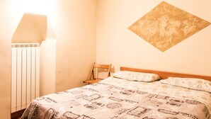 Une chambre à coucher comprenant un lit, une chaise, un radiateur et une œuvre d’art accrochée au mur.