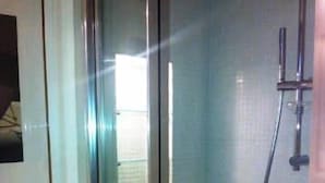 Un box de ducha con paredes de cristal y un cabezal de ducha manual.
