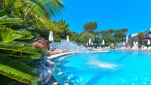 A large pool with water features, surrounded by palm trees and lounge chairs. - Hotel Pineta (Ischia)