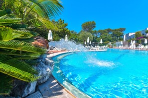 A large pool with water features, surrounded by palm trees and lounge chairs. - Hotel Pineta (Ischia)