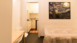 Un dormitorio con cama, una kitchenette pequeña y un comedor.