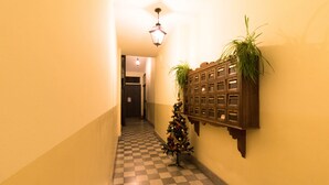 Un pasillo con piso a cuadros, un árbol de Navidad y un mueble de madera con plantas.