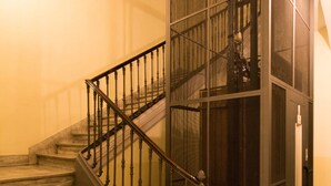 Una escalera con barandilla de metal negro y suelo a cuadros.