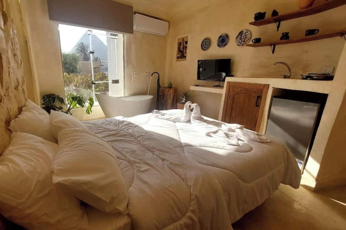A bedroom with a bed, a window, a sink, and a television.