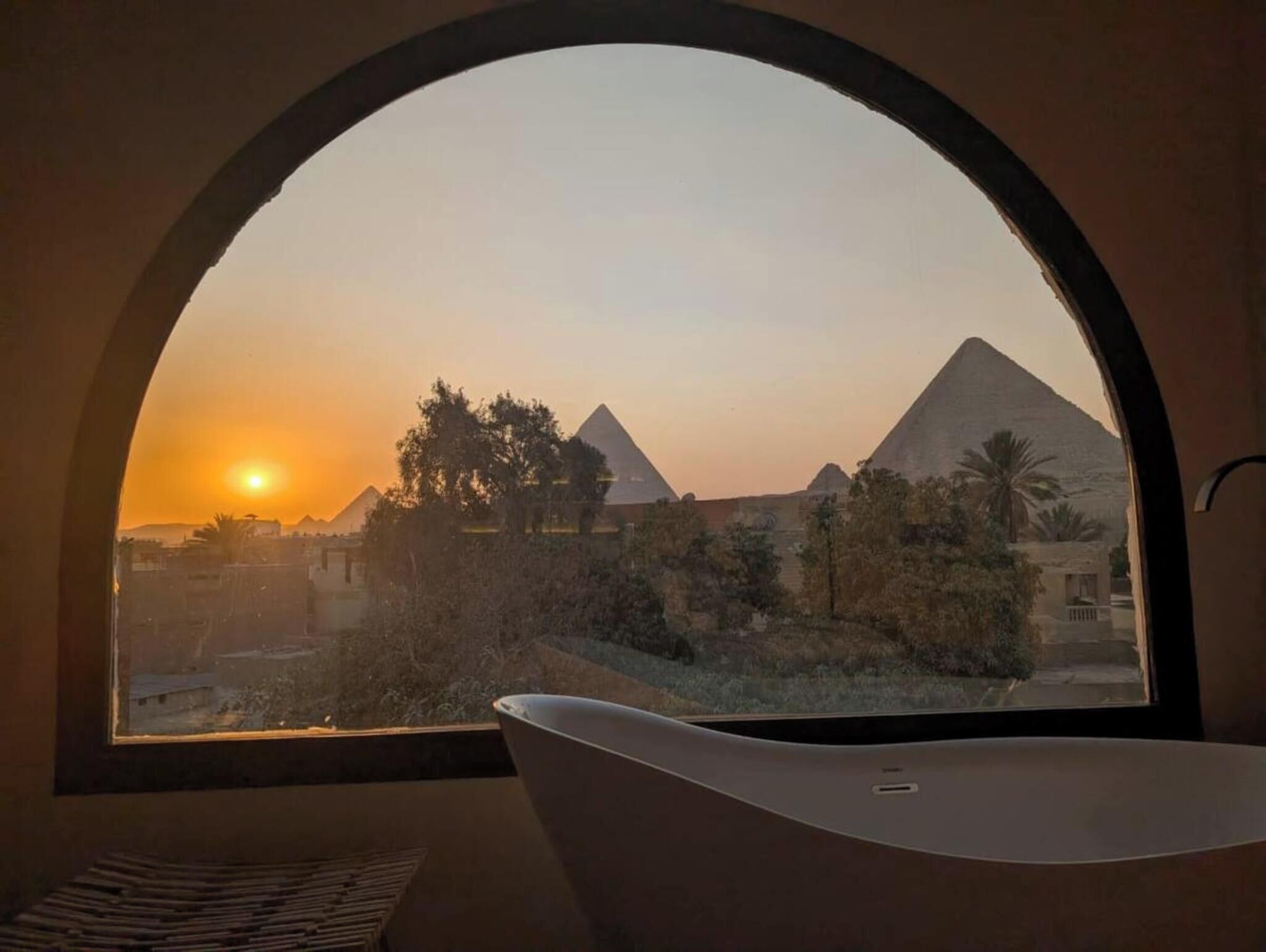 Una vasca da bagno in una stanza con vista sulle piramidi al tramonto.