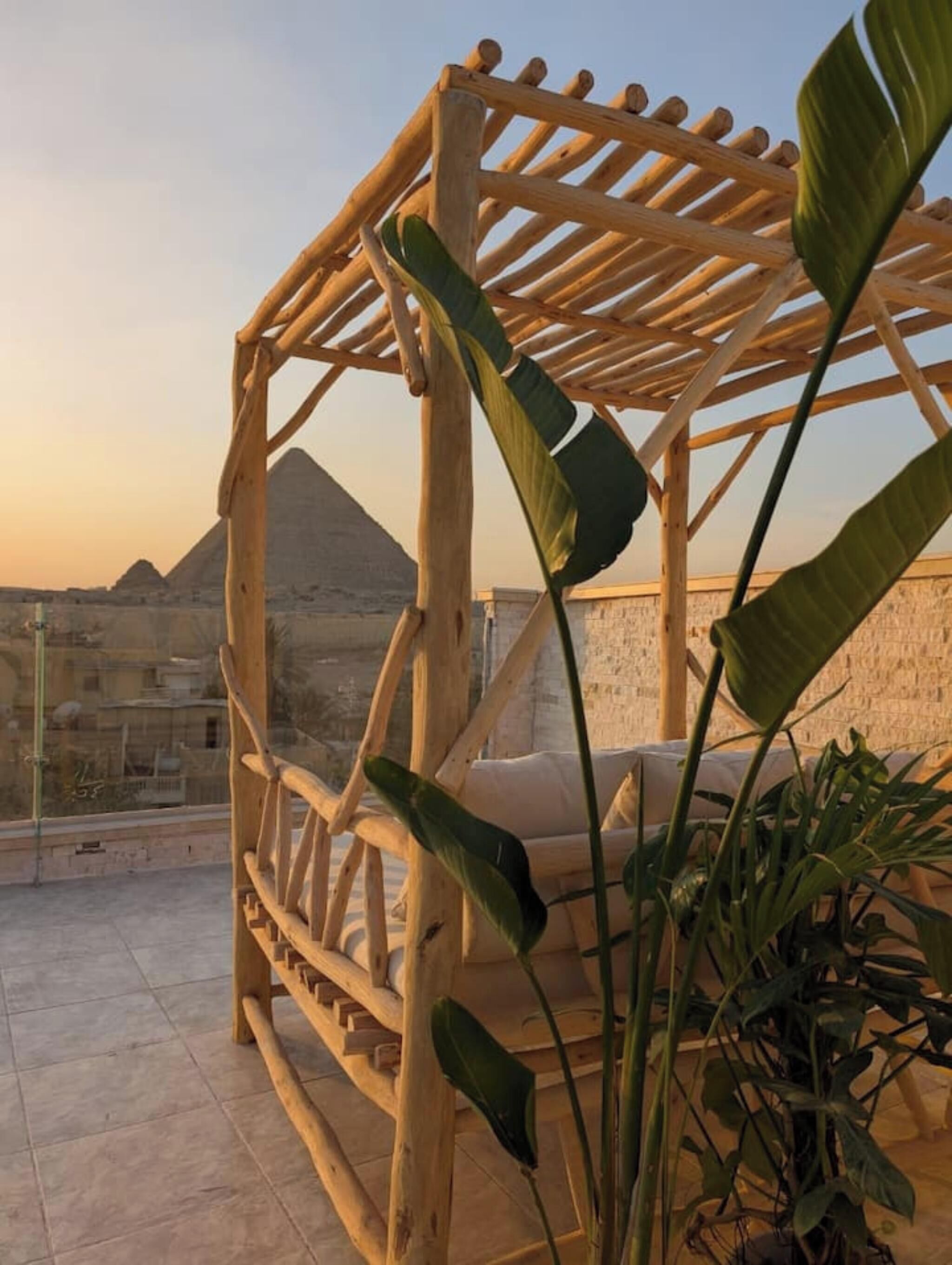 A wooden pergola structure with a view of a pyramid in the background.