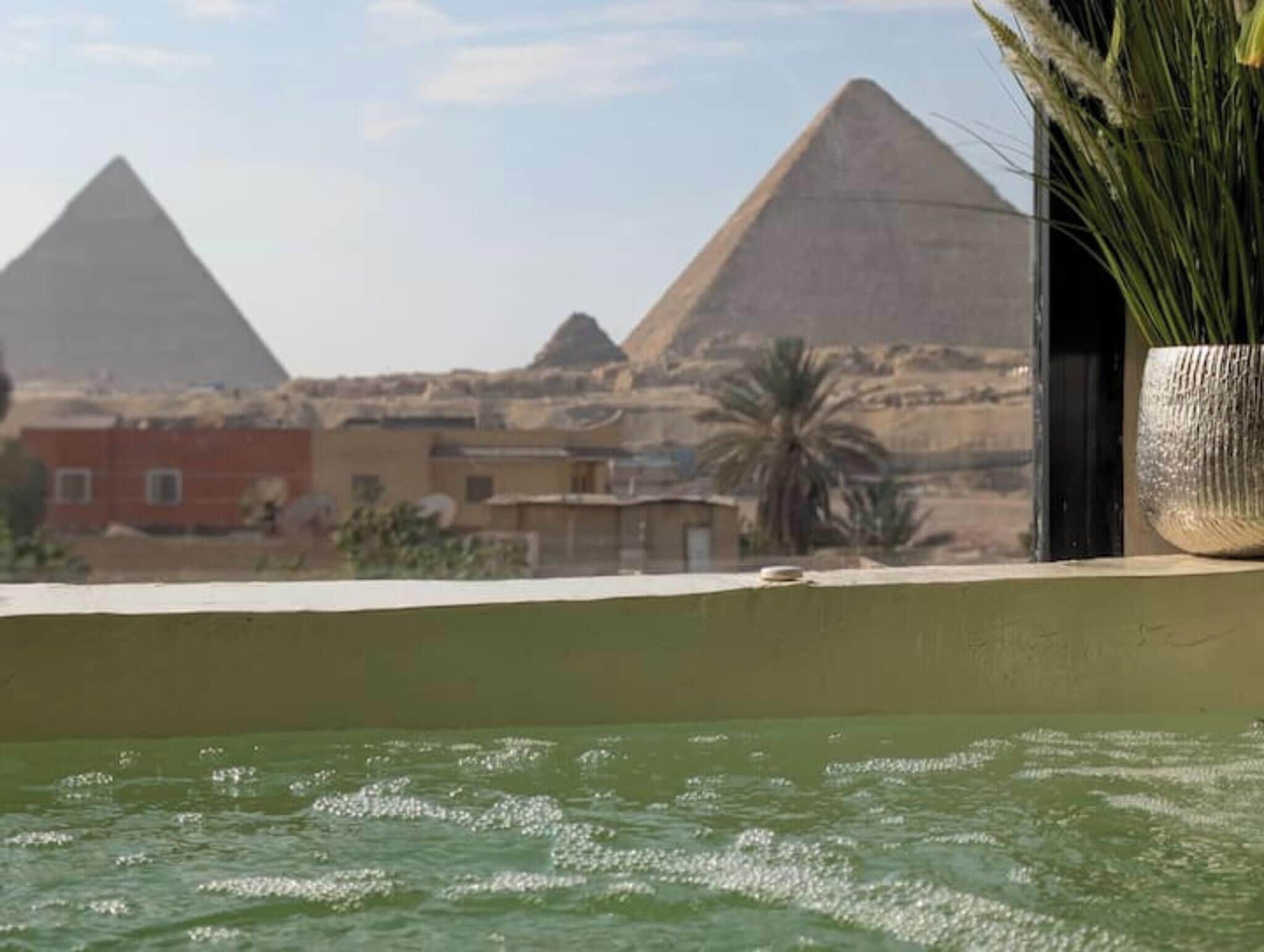 Vista de las pirámides al fondo y una piscina en primer plano.