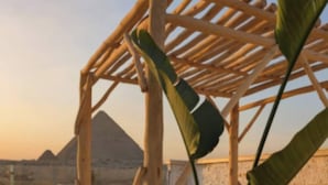 Une pergola en bois offrant une vue sur les pyramides en arrière-plan.