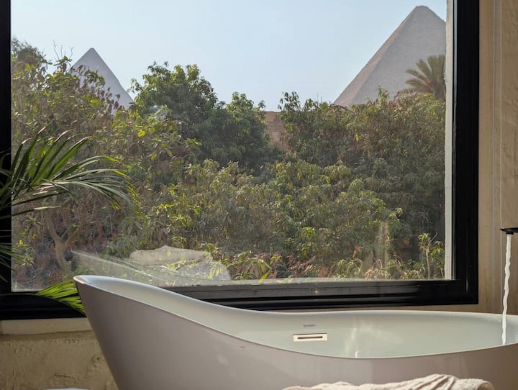 Une baignoire offrant une vue sur les pyramides et une végétation luxuriante.