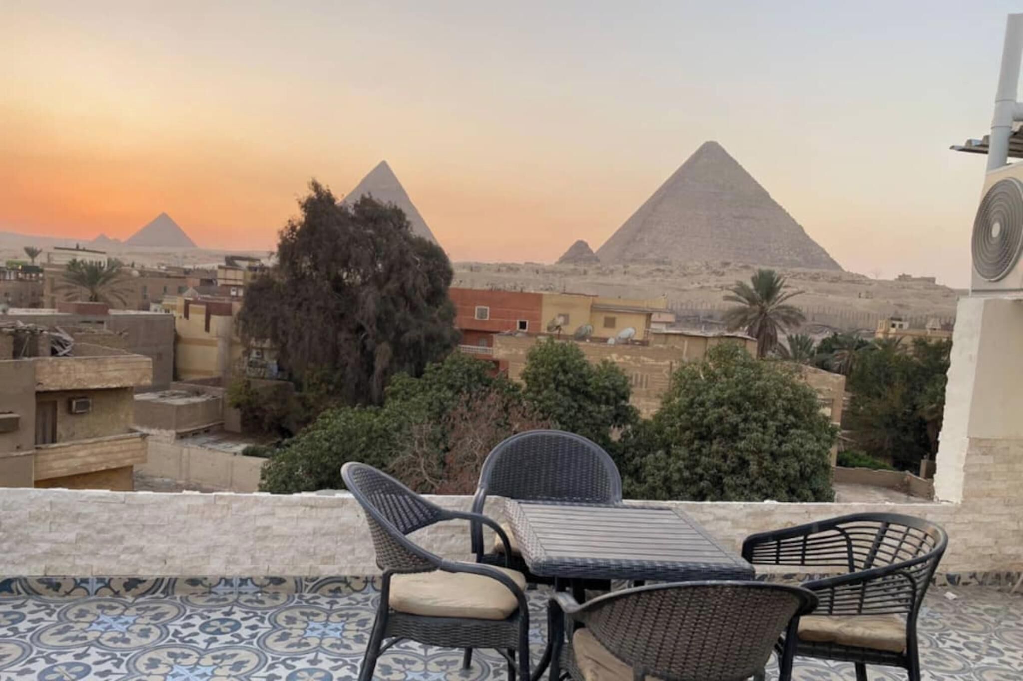 A terrace with wicker furniture, a patterned floor, and a view of the pyramids.